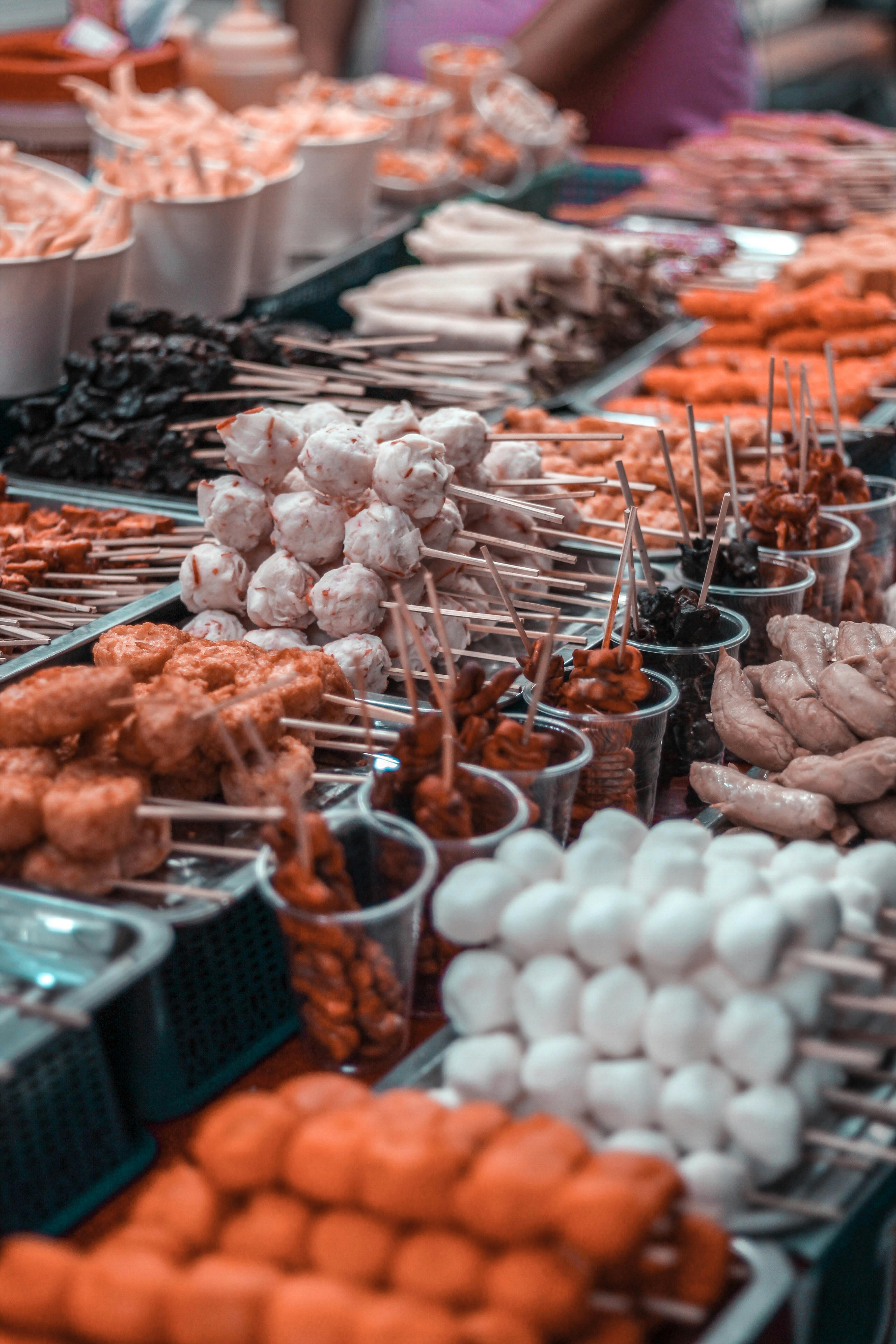 A street food market stall showcasing a variety of skewered delicacies like fish balls, squid balls, and other popular snacks.