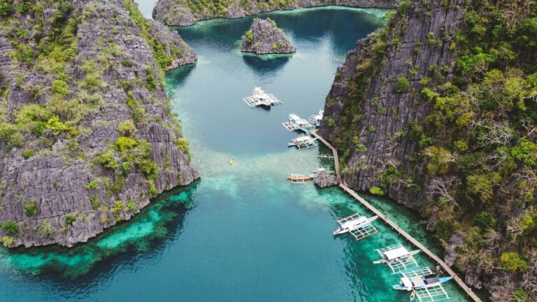 A turquoise lagoon in Coron, Palawan, surrounded by limestone cliffs and boats.