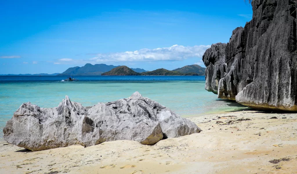 Beautiful beach in Coron, Palawan with limestone cliffs, turquoise sea, and rocky shoreline — one of the best beaches in Palawan and a top Philippines travel destination.

