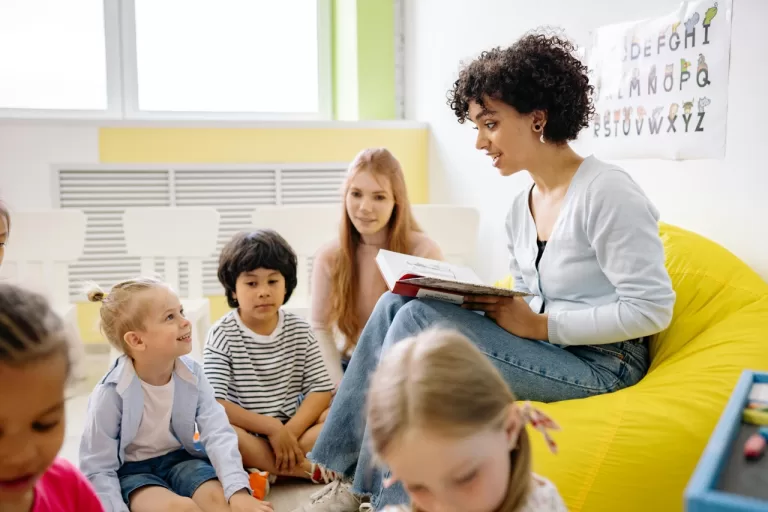 Pre-school classroom with a teacher reading a book to kids