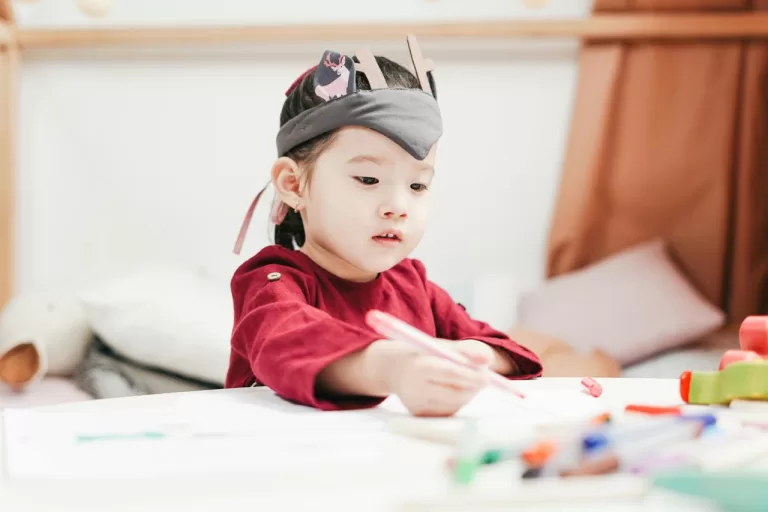 A toddler holing a colored pen