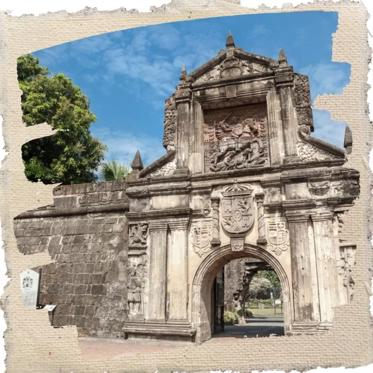 Historic stone gateway of Fort Santiago in Intramuros, Manila, featuring intricate carvings and a blue sky background.
