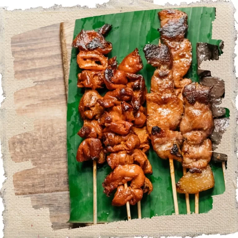 Filipino street food barbecue skewers (pork and chicken) served on a banana leaf, grilled to a caramelized finish.