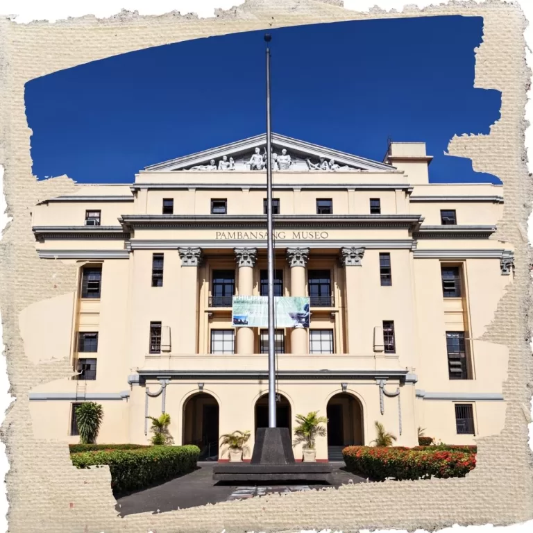 Front view of the National Museum of the Philippines (Pambansang Museo) with neoclassical architecture, a flagpole, and clear blue skies.