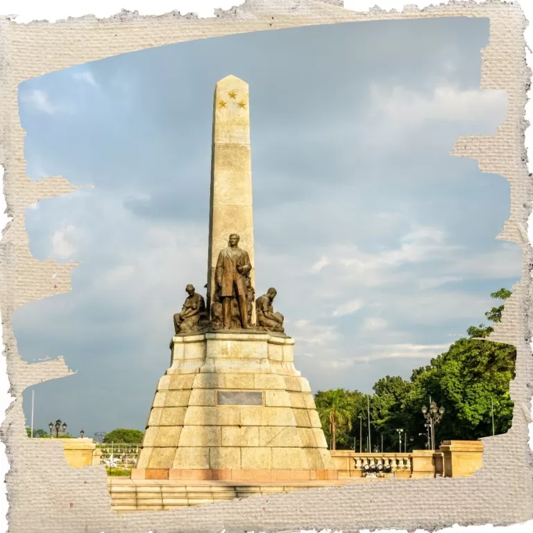 The Rizal Monument at Rizal Park in Manila, featuring a bronze statue of Dr. José Rizal with an obelisk and stone pedestal under a bright sky.