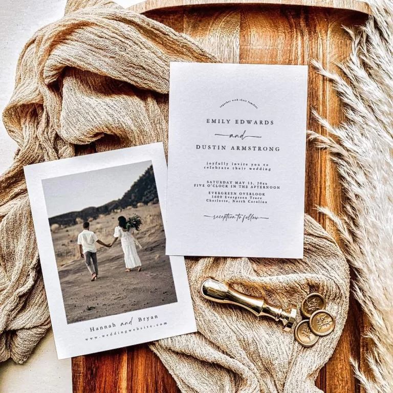 Flat lay of elegant wedding invitation cards on a wooden tray with beige fabric, a photo of a couple walking hand in hand, and a gold wax seal stamp.