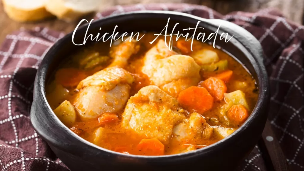 Filipino chicken afritada stew with potatoes, carrots, and tomato sauce in a black bowl.
