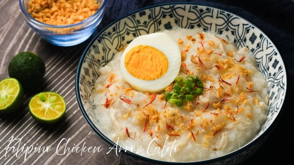 Filipino chicken arroz caldo with boiled egg, crispy garlic, and green onions in a patterned bowl.