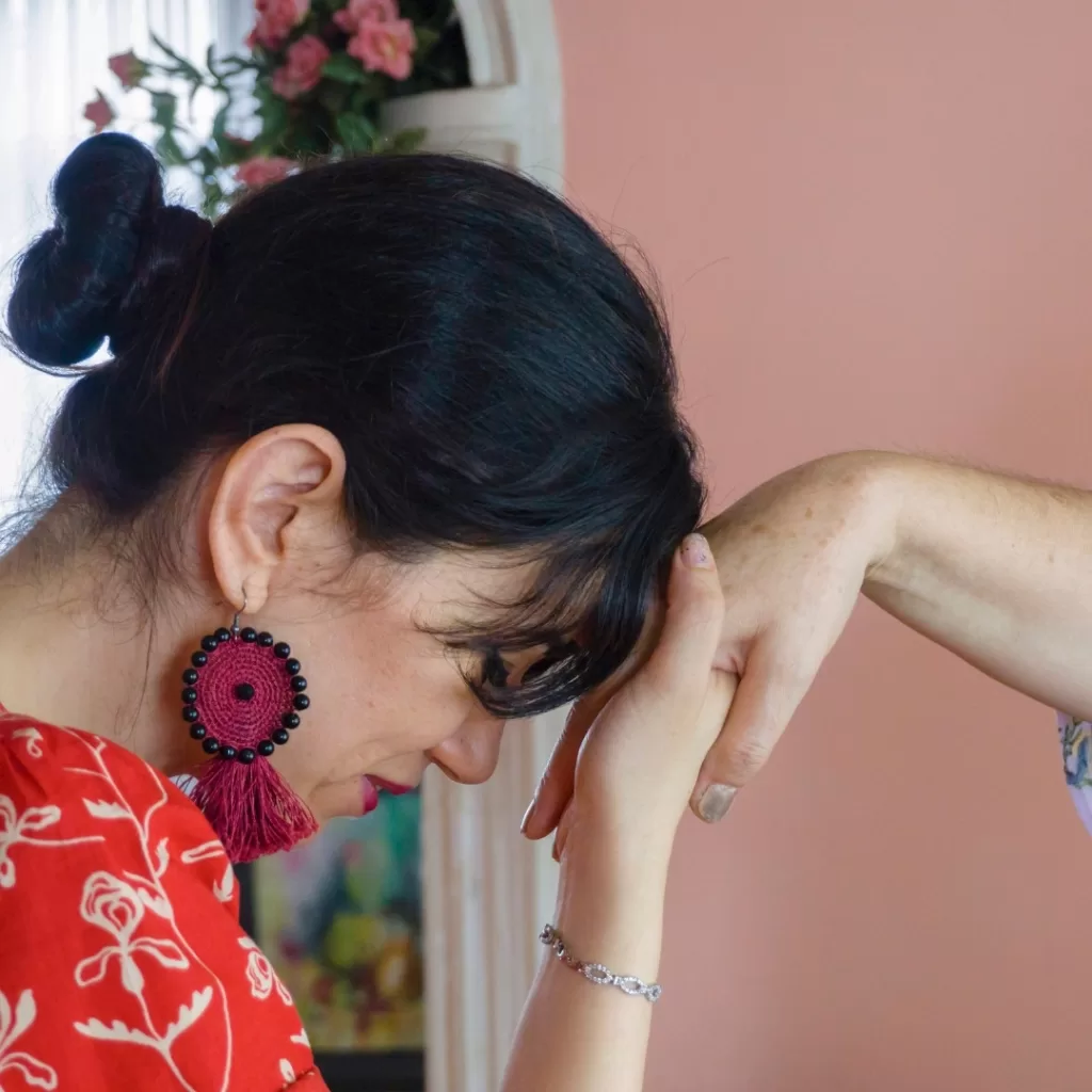 Filipina woman performing ‘mano po’ gesture by bowing her head to touch an elder’s hand—a traditional Filipino sign of respect and reverence for elders.