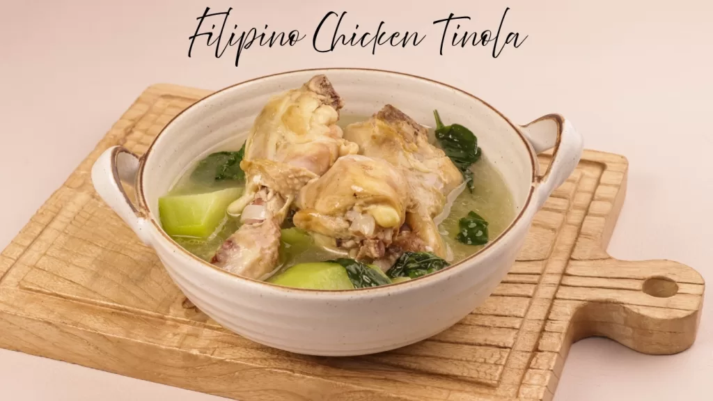 Filipino Chicken Tinola soup with green papaya and spinach in a ceramic bowl.