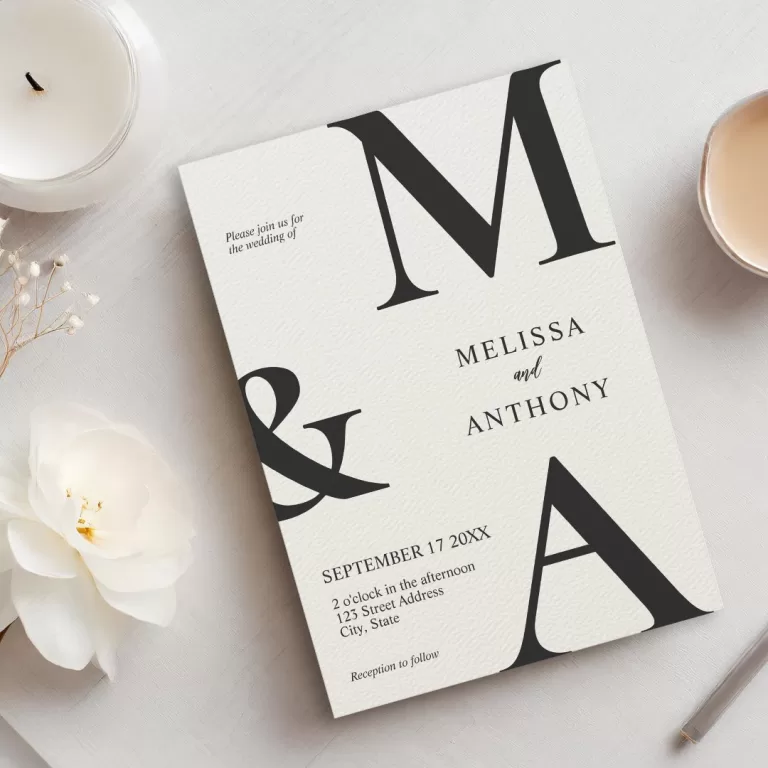Minimalist monogram wedding invitation featuring large initials “M & A” with elegant serif fonts, set on a textured cream background.